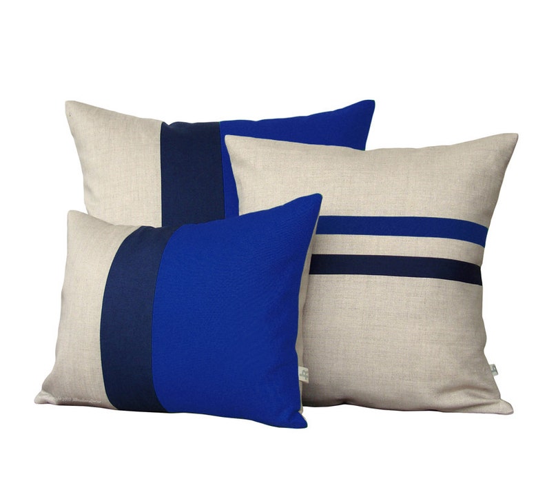 Puede incluir: Tres almohadas decorativas con base de tejido de lino y rayas azules y azul marino. Las almohadas est&aacute;n apiladas con la m&aacute;s grande en la parte inferior y la m&aacute;s peque&ntilde;a en la parte superior.