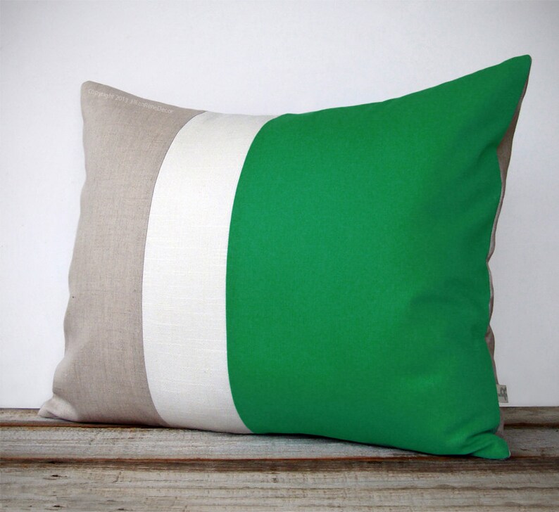 May include: A rectangular cushion with three horizontal stripes. The stripes are beige, white, and a bright green. The cushion is made of a soft, textured fabric.
