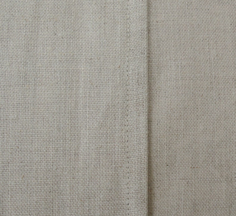 K&ouml;nnte beinhalten: Nahaufnahme eines beigefarbenen Stoffes mit einer geraden Naht in der Mitte.