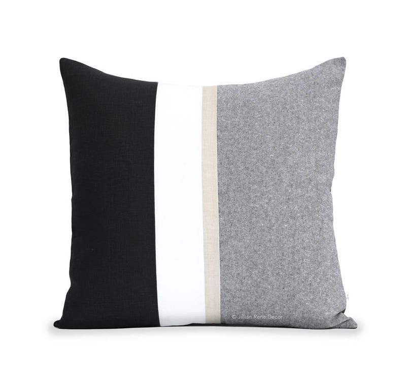 Puede incluir: Una almohada decorativa con un dise&ntilde;o de rayas negras, blancas y grises. La almohada est&aacute; hecha de una tela suave y texturizada.