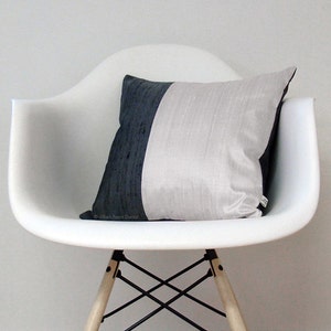 May include: A white chair with a black and white pillow. The chair has a wooden base and black metal legs.
