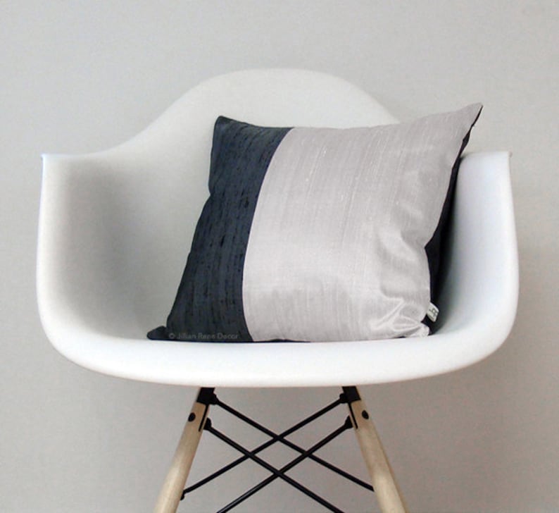 May include: A white chair with a black and white pillow. The chair has a wooden base and black metal legs.