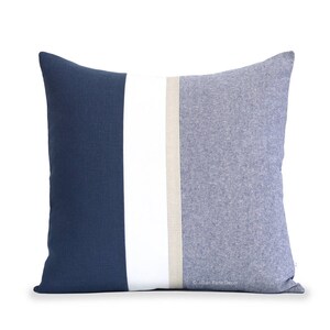 Op de afbeelding: Een blauw en wit gestreept kussen met een beige streep in het midden. Het kussen is gemaakt van een zachte, textuurrijke stof.