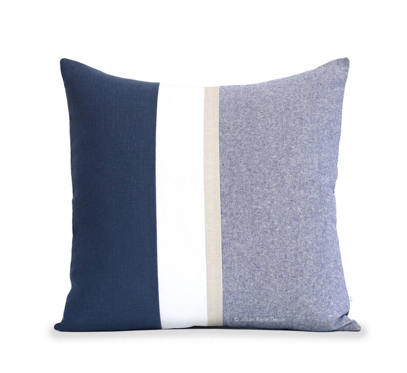 Op de afbeelding: Een blauw en wit gestreept kussen met een beige streep in het midden. Het kussen is gemaakt van een zachte, textuurrijke stof.