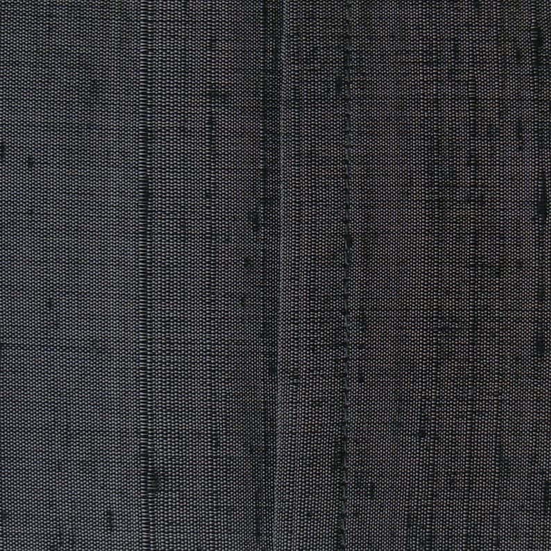 May include: Close-up of a black fabric with a subtle woven pattern. The fabric has a slightly textured surface.