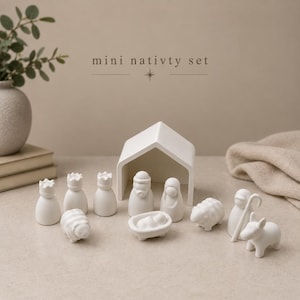 May include: A mini nativity set featuring white matte figurines including a stable, figures of people, and animals. The text "mini nativty set" is printed above the collection. The set includes stylized figures of a family, three kings, a sheep, and a donkey.