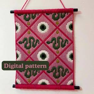 Peut inclure: Une tenture murale présentant un motif en losanges roses avec des serpents verts et des motifs circulaires blancs et verts alternés. Le textile est suspendu à deux tiges en bois noir avec un enroulement de fil rouge. Le texte Digital pattern est visible.