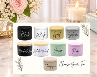 May include: A collection of nine cylindrical metal tins in various colours including black, white, gold, silver, green, pink, and champagne, with some featuring wood-look lids. Each tin is labelled with its colour name in cursive script.