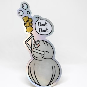 May include: A holographic sticker depicting a cartoon character playing a golden instrument, with bubbles above. The character is in a white outfit, and a speech bubble says "Doot Doot".