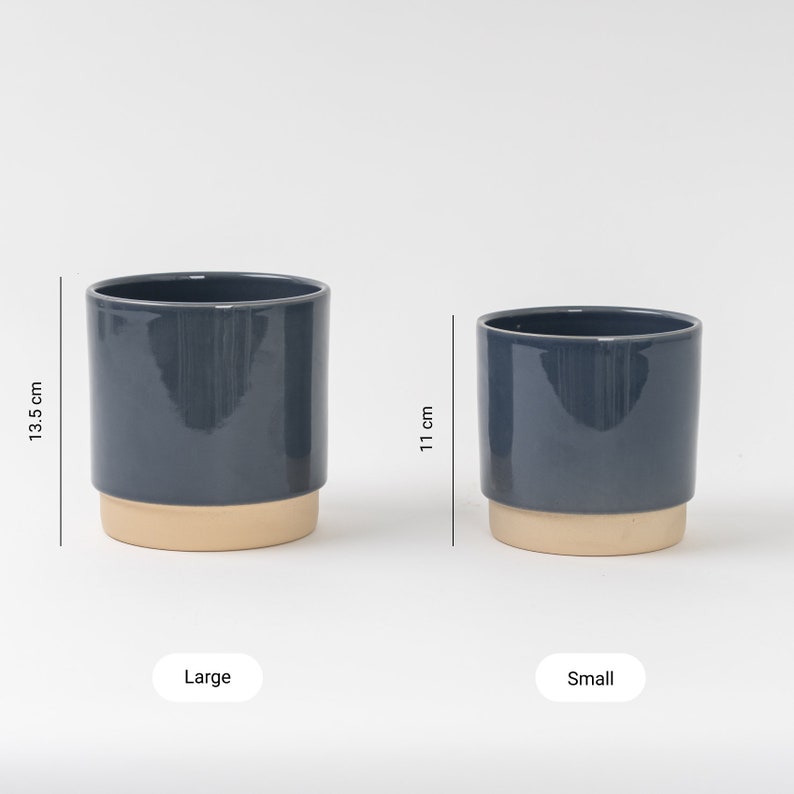 May include: Two ceramic plant pots, one large and one small, in a dark blue glaze with a beige rim. The large pot is 13.5 inches tall and the small pot is 11 inches tall.