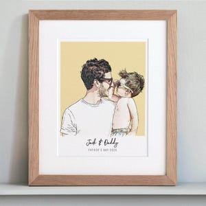 May include: A framed art print featuring a father and child in a tender moment, both wearing sunglasses. The artwork is set against a yellow background, with the text "Jack & Daddy" and "FATHER'S DAY 2025" at the bottom. The frame is made of light-colored wood.