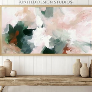 May include: Abstract painting in shades of pink, green, and brown. The painting is framed in a light wood frame and is hanging on a white wall.
