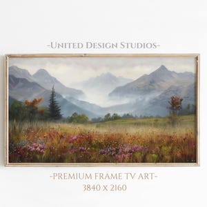 May include: A framed painting of a misty mountain landscape with a field of wildflowers in the foreground. The mountains are a soft blue and gray, and the sky is a pale blue. The painting is in a wooden frame.