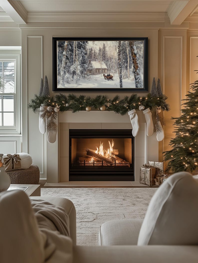 May include: A cozy living room with a fireplace, a Christmas tree, and a framed winter scene painting above the mantle. The fireplace is lit and there are stockings hung on the mantle. The room is decorated with a garland of greenery and lights.