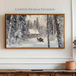 May include: A framed winter landscape painting depicting a snowy forest scene with a small wooden cabin and a horse-drawn carriage. The painting is in a gold frame and is hanging on a white wall.