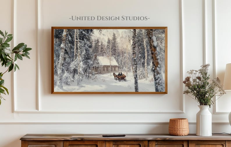 May include: A framed winter landscape painting depicting a snowy forest scene with a small wooden cabin and a horse-drawn carriage. The painting is in a gold frame and is hanging on a white wall.