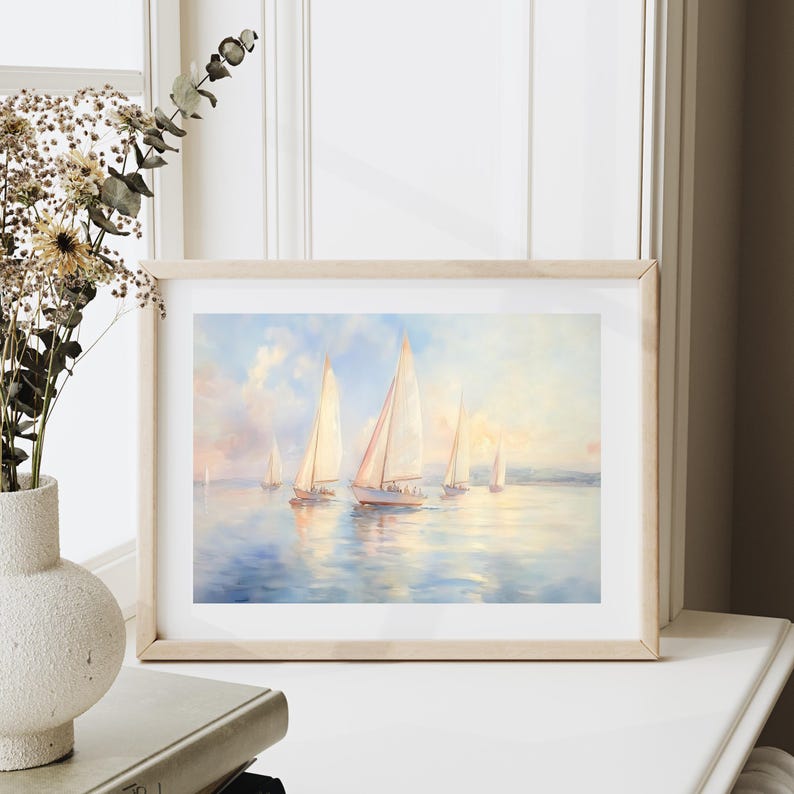 Puede incluir: Una pintura enmarcada de veleros en un cuerpo de agua azul tranquilo. El cielo es de un azul suave y p&aacute;lido con nubes tenues. Los veleros son blancos y tienen un brillo dorado c&aacute;lido. La pintura est&aacute; enmarcada en un marco de madera claro.
