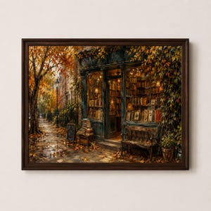May include: A framed wall art print depicting a bookstore exterior during autumn. The scene features a dark storefront filled with bookshelves, a wooden bench, a stack of books on the sidewalk, and trees with orange leaves lining a city street.