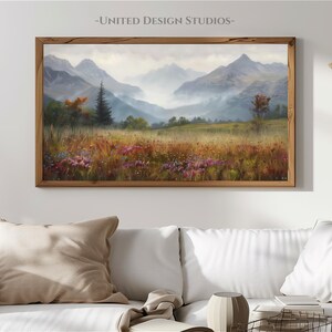 May include: A framed painting of a mountain landscape with a misty valley and a field of wildflowers in the foreground. The mountains are in the background and are covered in fog. The painting is in a wooden frame.