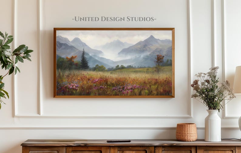 May include: A framed painting of a misty mountain landscape with a valley in the foreground. The painting features a variety of colors, including green, brown, and blue. The mountains are covered in fog, and the valley is filled with wildflowers.