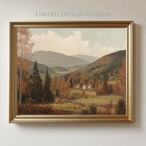 Op de afbeelding: Een ingelijst landschapsschilderij met een goudkleurige lijst. Het kunstwerk toont een vallei met bergen, bomen en kleine gebouwen. De tekst "-UNITED DESIGN STUDIOS-" staat bovenaan de afbeelding.