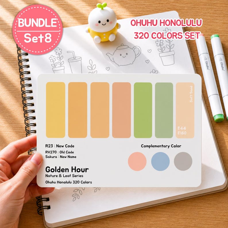 May include: A set of Ohuhu Honolulu 320 Colors markers with a color palette card featuring shades of yellow, orange, and green. The card includes the text "Golden Hour" and "Nature & Leaf Series". A small, yellow figurine sits on a spiral notebook.