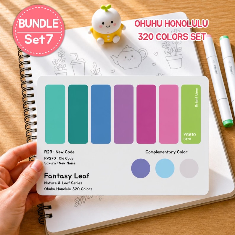 May include: A color palette card from the Ohuhu Honolulu 320 Colors Set, featuring a range of colors from teal to pink, with the text "Fantasy Leaf." The card is held over a spiral-bound notebook. A small, yellow figurine and markers are also visible.