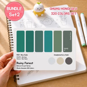 May include: A color palette card from the Ohuhu Honolulu 320 Colors Set, featuring shades of green. The card includes the text "Rainy Forest" and color codes. Two white markers and a small yellow figurine are also visible.