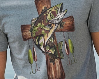 Könnte beinhalten: Ein graues T-Shirt mit einem Aufdruck eines Barsches auf einem Holzkreuz, an dem Angelköder hängen.