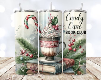 May include: A white tumbler with a winter scene featuring a candy cane, a cup of hot chocolate with whipped cream and a sprig of holly, and a stack of books. The text "Candy Cane Book Club" is printed on the tumbler.