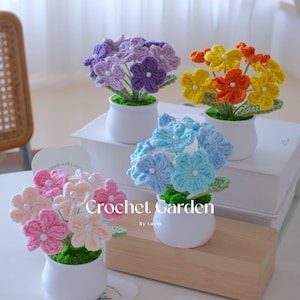 Puede incluir: Una colección de flores de ganchillo hechas a mano en pequeñas macetas blancas. Las flores son de varios colores, incluyendo rosa, azul, amarillo, naranja y morado. El texto "Crochet Garden" es visible.