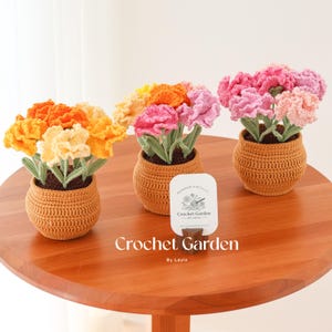 May include: Three crocheted flower arrangements in brown pots on a wooden table. The flowers are pink, orange, and yellow. The pots are made of crocheted yarn. A sign reads "Crochet Garden by Layla".