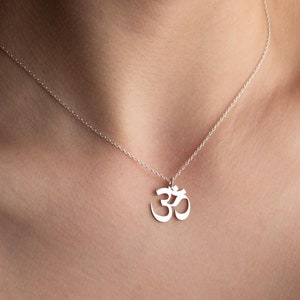 May include: A silver necklace with an Om symbol pendant. The necklace is delicate and simple, making it a perfect choice for everyday wear.
