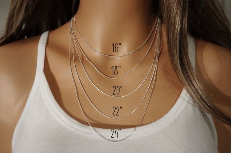 May include: Five thin silver-toned snake chains layered at different lengths. The chains are labeled with their respective lengths in inches: 16 inches, 18 inches, 20 inches, 22 inches, and 24 inches, providing a clear visual guide for necklace sizing.