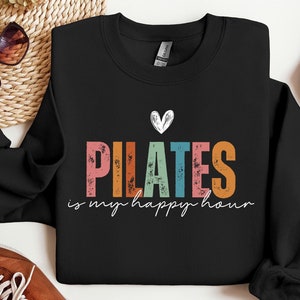 May include: Black sweatshirt with a rainbow coloured "PILATES is my happy hour" graphic and a small heart above the text.