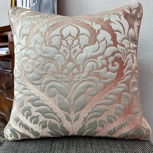 Peut inclure: Un coussin décoratif avec un motif damassé dans des tons de vert et de rose.