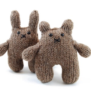 Puede incluir: Dos animales de peluche de punto marrón, uno un conejo y otro un oso, con ojos y narices negros.