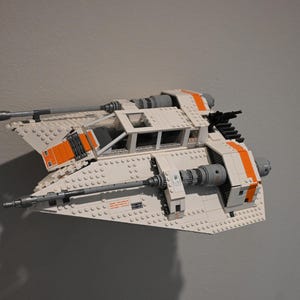 Peut inclure: Un vaisseau spatial Lego blanc et orange avec un cockpit transparent et deux canons sur le côté.