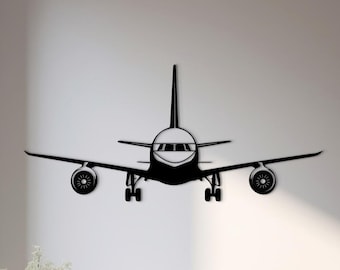 May include: A black metal wall art piece shaped like the front view of a commercial airplane. The silhouette features a central fuselage, two wings with visible engine turbines, a vertical stabilizer, and landing gear components.