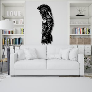 May include: Black metal wall art depicting a Spartan warrior in profile. The artwork features a detailed helmet, armor, and muscular physique. This decorative piece is suitable for home decor, adding a touch of historical and heroic theme.