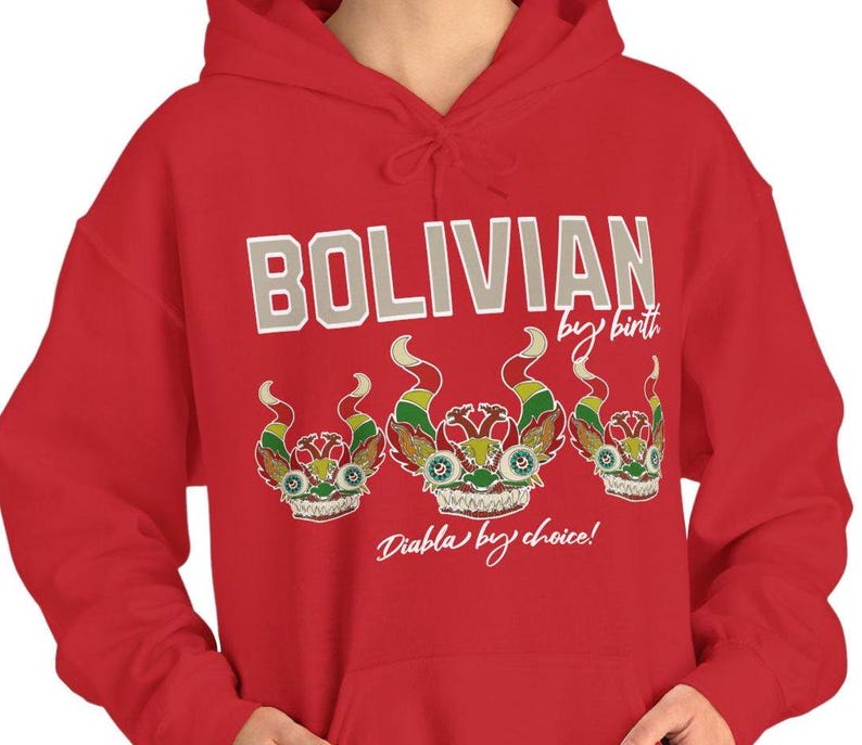 May include: Red hooded sweatshirt with the text "Bolivian by birth, Diabla by choice!" in white. Three colorful devil masks are printed below the text.
