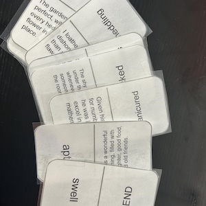 Peut inclure: Plusieurs cartes rectangulaires blanches aux coins arrondis, imprimées avec du texte et protégées par des pochettes en plastique transparent. Les mots "despise", "wedding", "apt", "swell" et "END" sont visibles.
