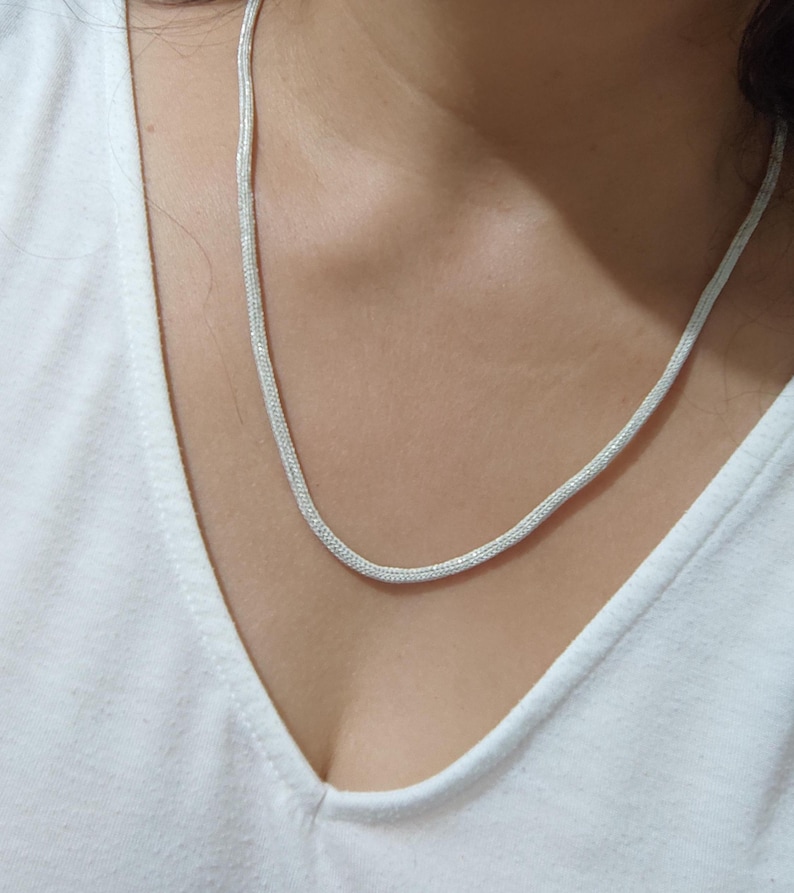 May include: A silver chain necklace with a delicate, snake-like design.