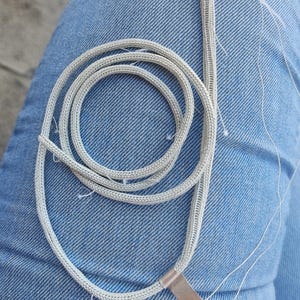 May include: A silver chainmail necklace with a silver metal clasp. The chainmail is made of small, interconnected metal rings.