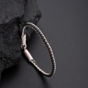 May include: A silver and black braided bracelet with a simple design.