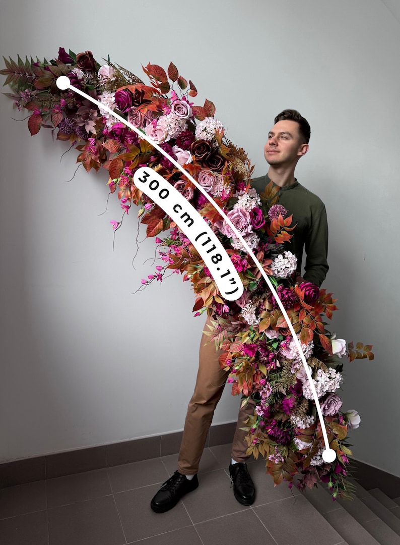 May include: A large floral arrangement, approximately 300 cm (118.1") long, featuring a cascade of burgundy, pink, and white flowers and foliage. The arrangement includes roses and other blooms, with a variety of textures and colours.