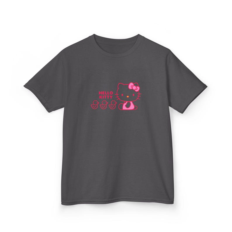 Puede incluir: Camiseta gris oscuro con un gr&aacute;fico rosa de Hello Kitty con lazo y tres chupetes. El texto "Hello Kitty" est&aacute; encima del personaje. La camiseta es de material suave.