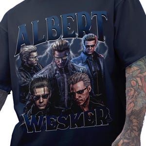 May include: A navy blue t-shirt with a graphic print of Albert Wesker from the Resident Evil video game series. The graphic features five different versions of Wesker, with the text "Albert Wesker" printed above the image.