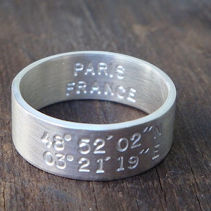 Peut inclure: Une bague en argent gravée avec "Paris France" et les coordonnées "48° 52' 02" N 03° 21' 19" E".
