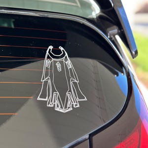 May include: A white outline of a spaceship on a black car window.